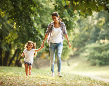 Mother and daughter playing and running around the park on beautiful morning.